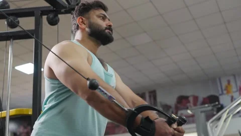 Indian young man using cable chest fly machine in modern gym Stock Footage 341856347