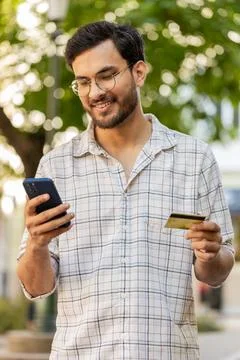 Indian young man using credit card smartphone while transferring money Stock Photos