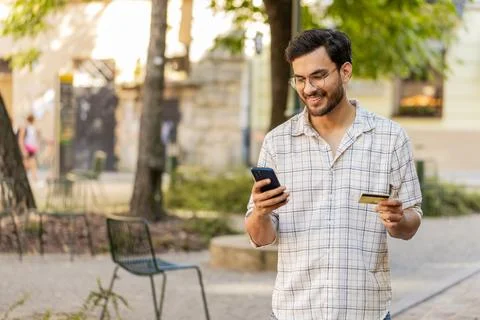 Indian young man using credit card smartphone while transferring money Stock Photos