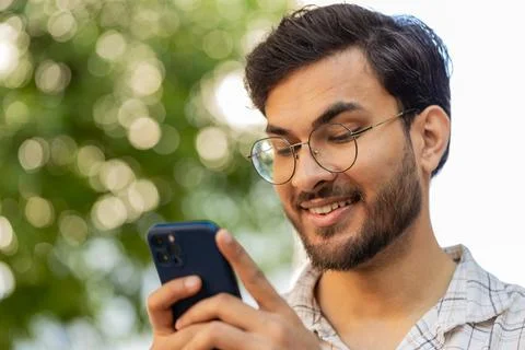 Indian young man using smartphone typing text messages in social media Stock Photos