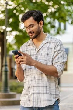 Indian young man using smartphone typing text messages in social media Stock Photos