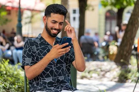 Indian young man using smartphone typing text messages in social media Stock Photos