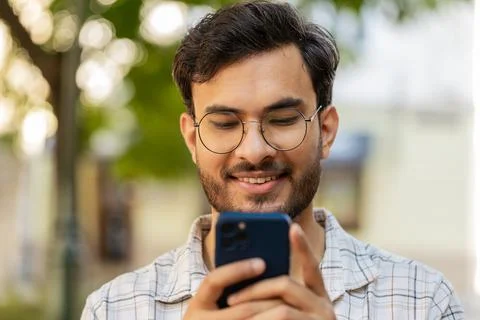Indian young man using smartphone typing text messages in social media Stock Photos