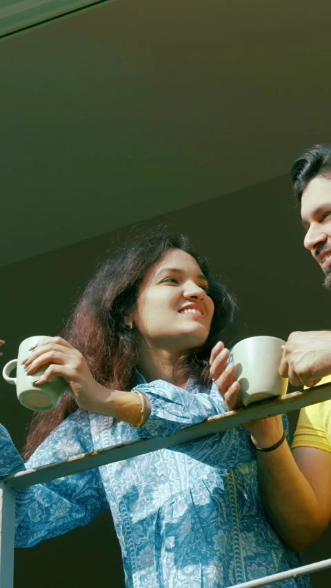 Indian young smart couple spending quality time standing at balcony chatting Stock Footage 343415420
