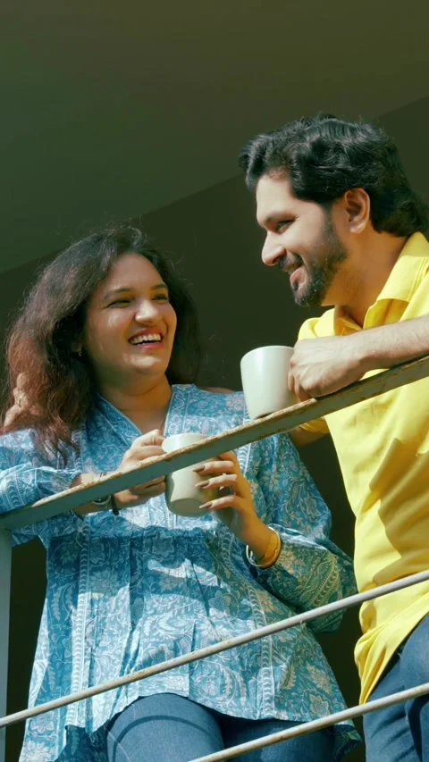 Indian young smart couple spending quality time standing at balcony chatting Stock Footage 343415448