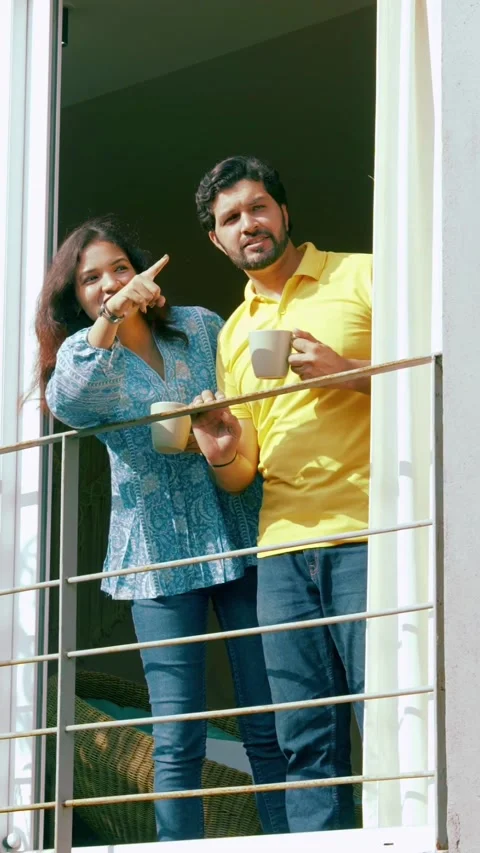 Indian young smart couple spending quality time standing at balcony chatting Video stock 343415567