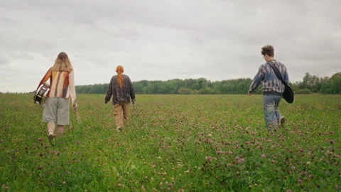 Indie Band Members Walking with Instruments Across Field Stock Footage 345470764
