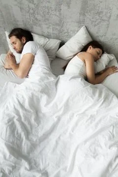 Indifferent couple sleep separately avoiding intimacy in bed Foto stock