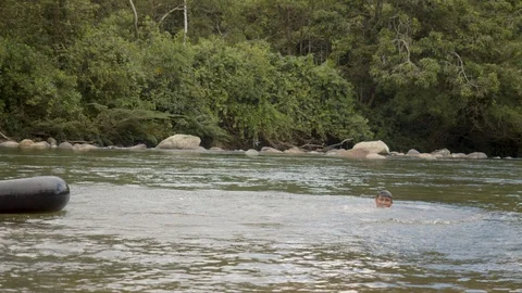 An indigenous boy falls into a water from a floating tire general shot reverse Stock Footage 113179555