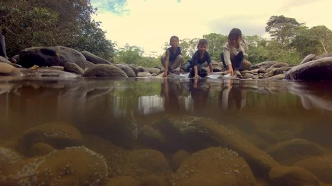 Indigenous kids having fun playing with paper boats on the river in the amazon Stock Footage 113593463