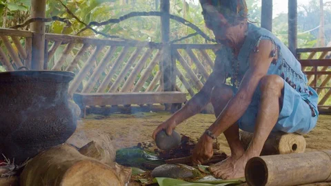 Indigenous man crushing ayahuasca sticks to prepare traditional drink in the Stock Footage