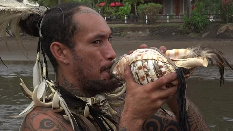 Indigenous man with tattoos blows conch shell horn, Nuku Hiva, French Polynes Stock Footage 109648854