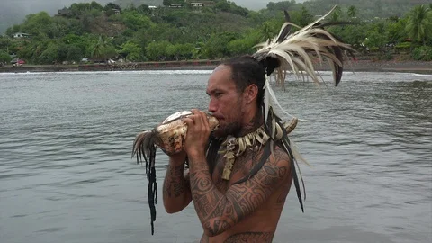 Indigenous man with tattoos blows conch shell horn, Nuku Hiva, French Polynes Stock Footage 109649407