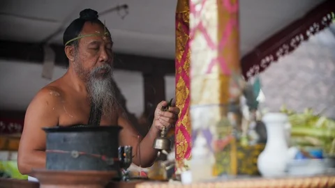 Indigenous priest ringing a bell for the Melukat Mebayuh Ceremonial, Bali Stock Footage 140296775