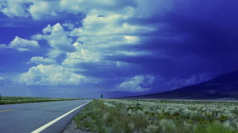 Indigo storm clouds over lonely road with prairie grass and mountain Stock Footage 44230756