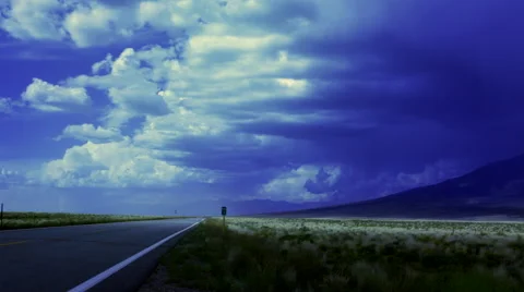 Indigo storm clouds over lonely road with prairie grass and mountain Stock Footage 44230993