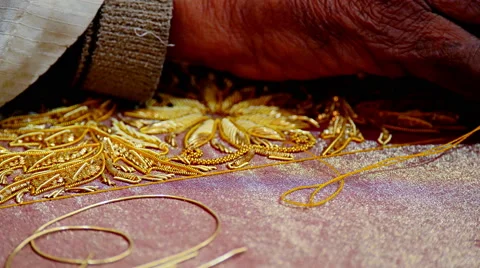 Indin craftsman sews / threads gold beads onto fabric, close up Stock Footage 51361009