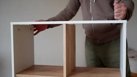 An individual is assembling a white cabinet drawer, showcasing DIY furniture Stock Footage 302657965