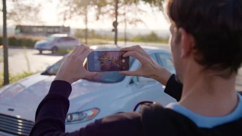 Individual capturing image of a car using smartphone, showcasing modern Stock Footage 316834906