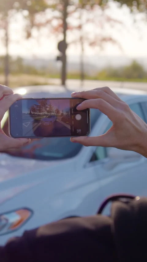 Individual capturing image of a car using smartphone, showcasing modern Stock Footage 319944964