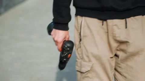 Individual in cargo pants with drill on city sidewalk. Construction worker in Vídeo Stock 334946220