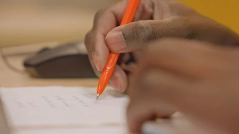 An individual diligently notes important information beside computer equipment Stock Footage 346212455