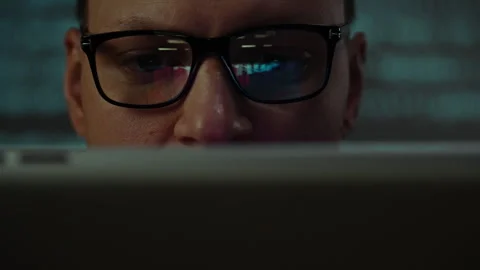 Individual engaged in focused work with computer screen reflecting vivid col Stock Footage 301404933
