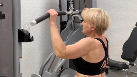 An individual is engaged in an intense workout session using a cable pulley Stock Photos