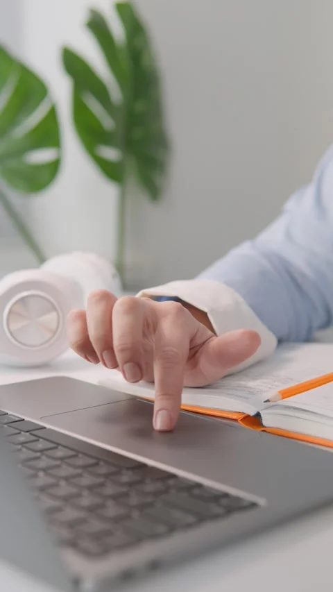 An individual is focused on using a laptop and making notes in a notebook Stock Footage 283203449