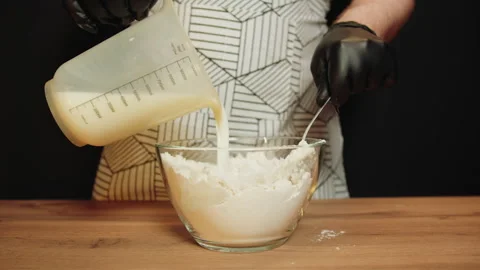 Individual gently blends milk from jar with flour in kitchen Video stock 330536568
