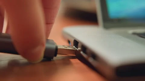 Individual gently connecting cord to computer in studio scene. Professional Stock Footage 337365601