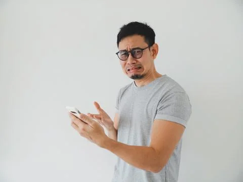 Individual grimaces while viewing smartphone content critically Stockfoto's