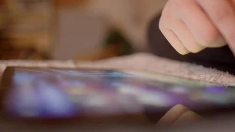 An individual is interacting with a tablet device while it rests on a textured s Stock Footage 295932416