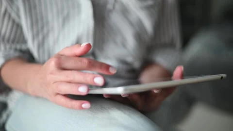 Individual interacts with a tablet while seated, displaying hand movements on Stock Footage 336778563