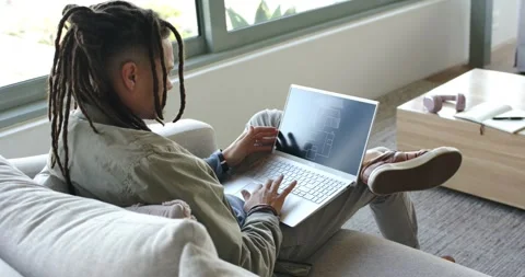 Individual opening silver laptop on couch by window and reviewing floor plan for Stock Footage 340069155