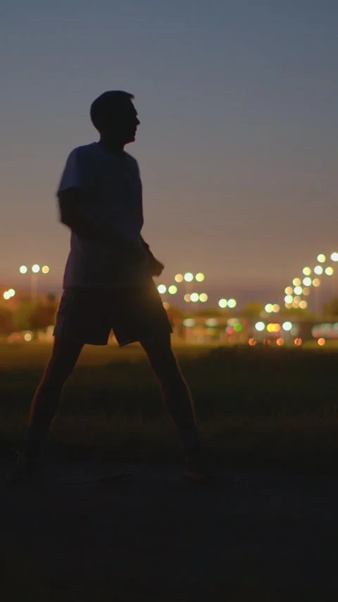 Individual practicing side bends under city lights during sunset Stock Footage 324591359