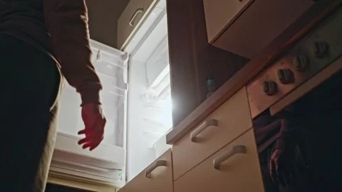 An individual is reaching into an open refrigerator located in a modern, stylish Video stock 309245126
