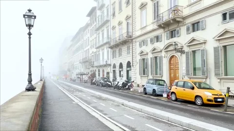 An individual rides an e-scooter along a foggy riverfront street Stock Footage 264711706