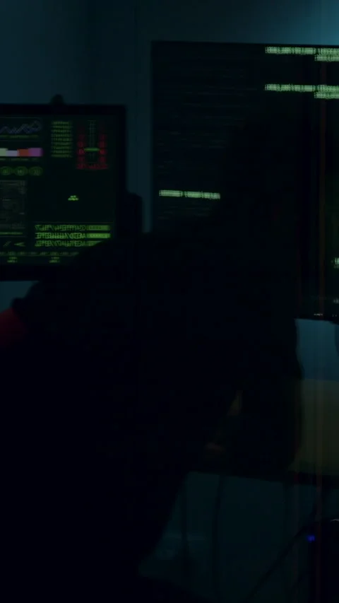 Individual seated at a desk, focused on multiple computer screens displaying Video stock 313927108