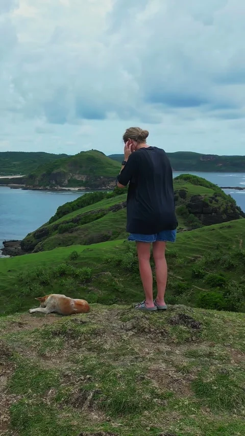 Individual standing alone on cliff watching expansive turquoise ocean Stockbeeldmateriaal 335223314