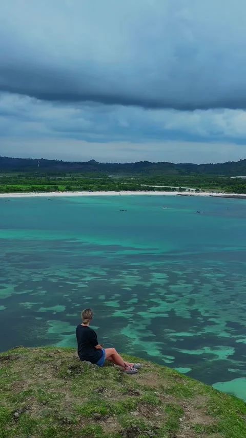 Individual standing alone on cliff watching expansive turquoise ocean 库存影片 335223356
