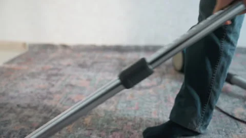 Individual systematically sweeping textured household carpet. Casually dressed Stock Footage 337462081