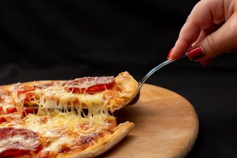 An individual is using a fork to take a delicious slice of pizza Stock Photos
