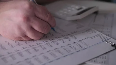 Individual Using Pen And Calculator For Data Annotation At Workspace, Focused Stock Footage 327336006