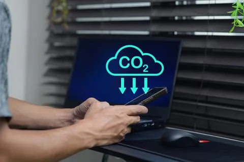 Individual Using Smartphone Near Computer Displaying CO2 Concept Stock Photos