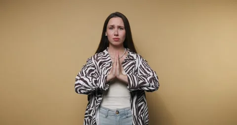 Individual in zebra-patterned jacket expresses hope and gratitude with hand.. Stock Footage 316179601