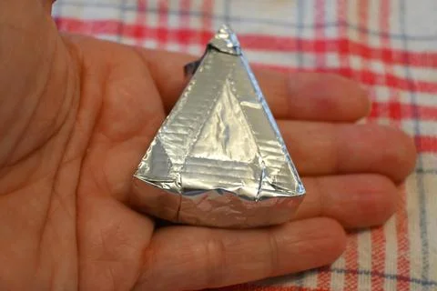 Individually wrapped processed cheese portion in a hand Stock Photos