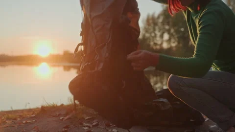 Individuals assembling their camping tent beside calm water at sunset. Closeup 스톡 동영상 332518549