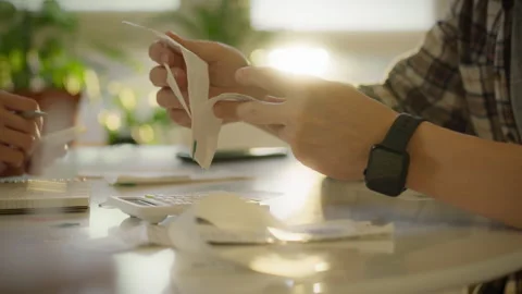 Individuals examining documents at a table with a smartphone and plants in a Stock Footage 323865379