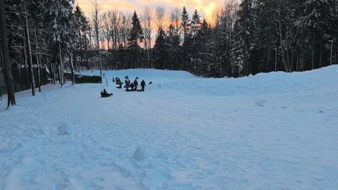 Individuals take pleasure in sledding down a snowy hill within a picturesque win Stock Footage 345207718